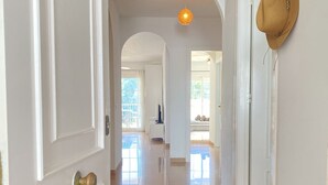 A hallway with white doors, a light fixture, and a view into a room with a bed and window. - Mediterraneo 20E by Casasol (Nerja)