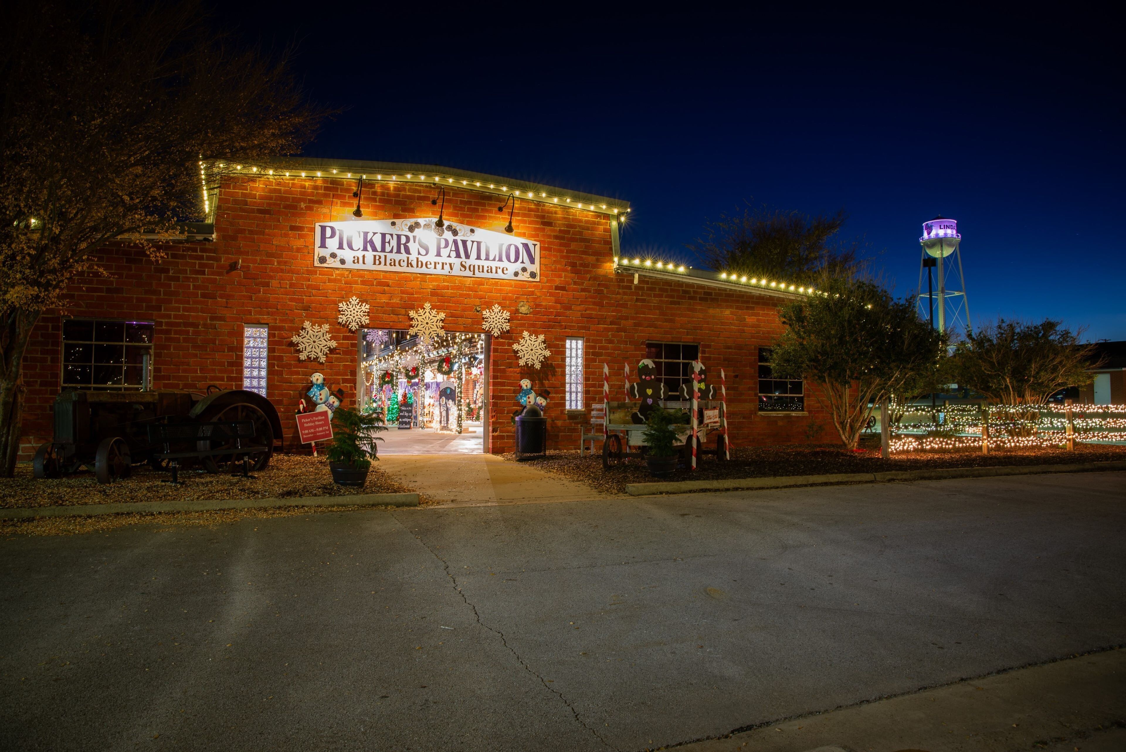 Picker's Pavilion at Blackberry Square, featuring a brick facade, a Christmas display, and a water tower in the background.