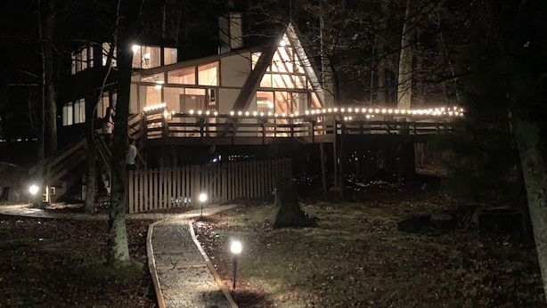 A house with a wooden deck and a triangular roof, surrounded by trees.