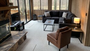 A cozy living room with a fireplace, a sofa, a coffee table, and a TV.