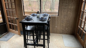 A dining area with a table set for four, a window with a view of trees, and a wooden door.