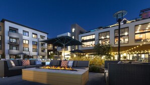 An outdoor seating area with a fire feature, lounge chairs, and umbrellas. - Luxury Condos Menlo Park (Menlo Park)
