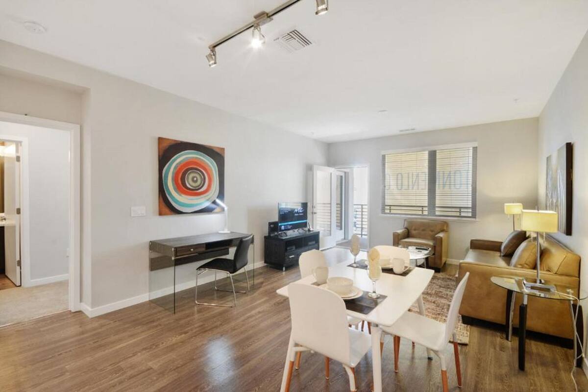 A modern living room with a dining area, a TV, and a sofa.