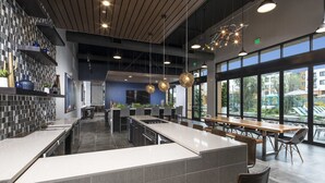 A modern kitchen with a central island, bar seating, and large windows offering views of the outdoors. - Luxury Condos Menlo Park (Menlo Park)