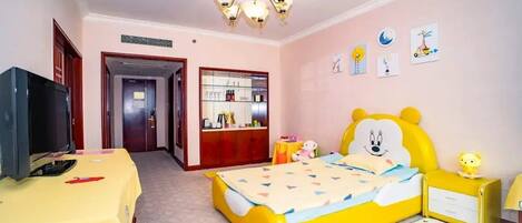 A child's bedroom with a yellow bed, a TV on a yellow table, a wardrobe, and a desk with a lamp.