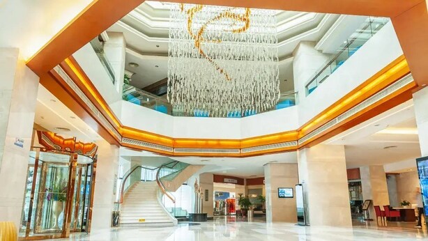 A spacious lobby with a central staircase, a chandelier, and a glass elevator. - Mianzhou Hotel (Mianyang)