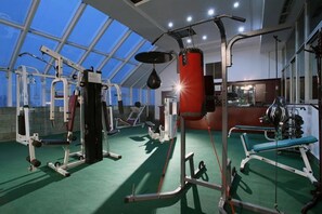 A gym with various exercise equipment, including a punching bag, weight machines, and benches. - Mianzhou Hotel (Mianyang)