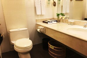 A bathroom with a toilet, a sink, a mirror, and a trash bin. - Mianzhou Hotel (Mianyang)