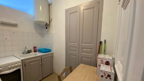 A kitchen with a stove, sink, and a white refrigerator. There is a wooden table and a box of Moulinex appliances. - Charming T1 full center Corte 13 cours paoli free wifi quiet bright (Corte)