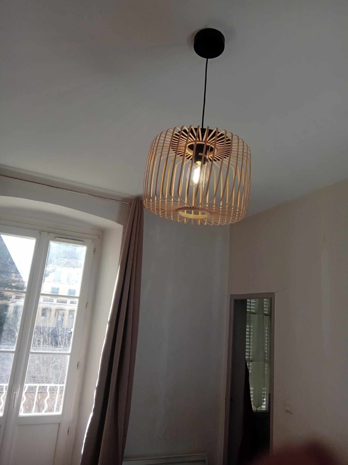 A room with a large window, a hanging light fixture, and a door.