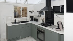 A modern kitchen with grey cabinets, a built-in oven, a microwave, and a coffee machine. - "Au Coin D'la Rue" Maison Avec Jardin à 2 pas de la Plage (Fécamp)