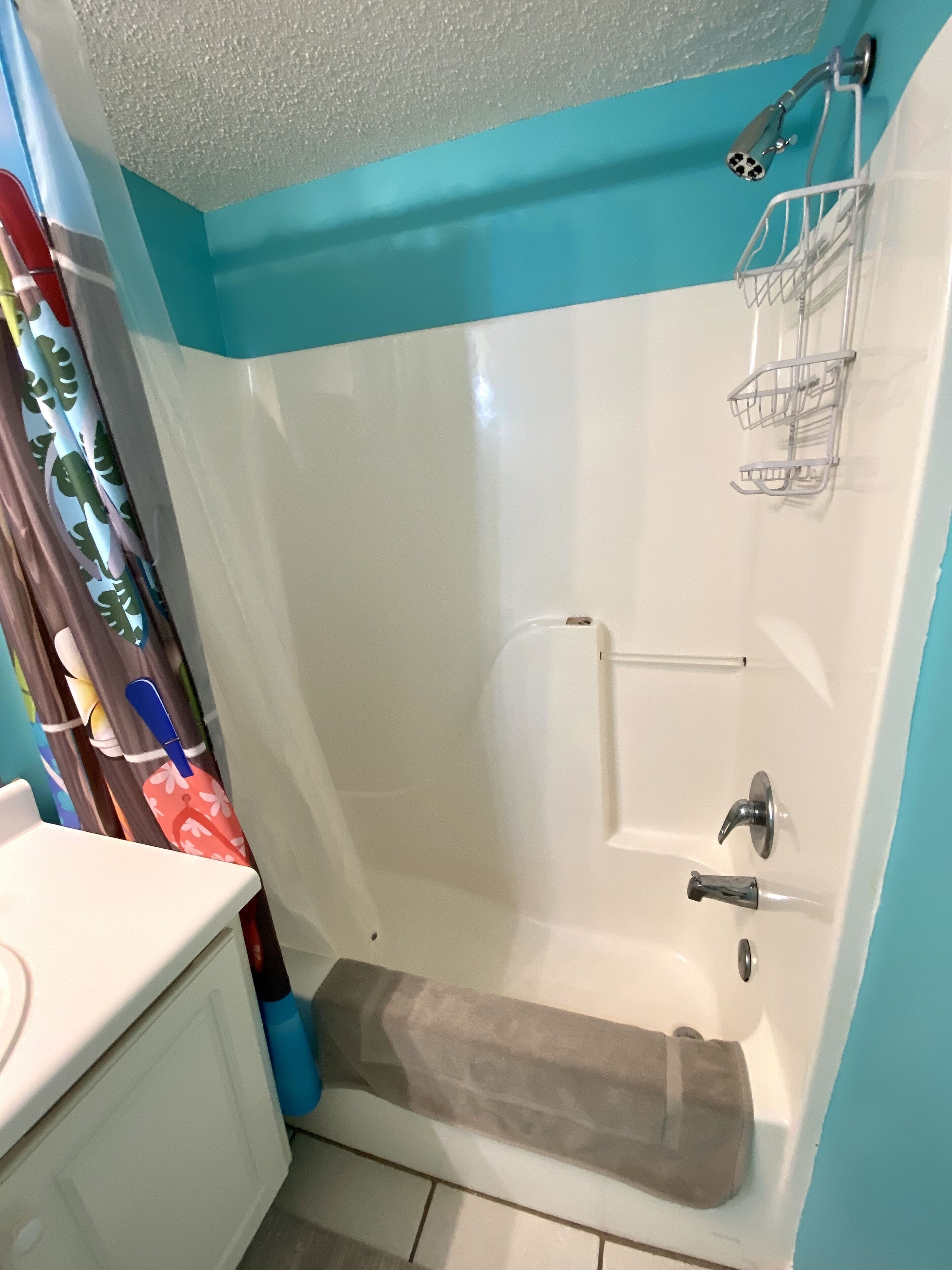 Une salle de bain avec une baignoire blanche, une douche, un porte-serviettes et un lavabo.