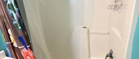 Une salle de bain avec une baignoire blanche, une douche, un porte-serviettes et un lavabo.