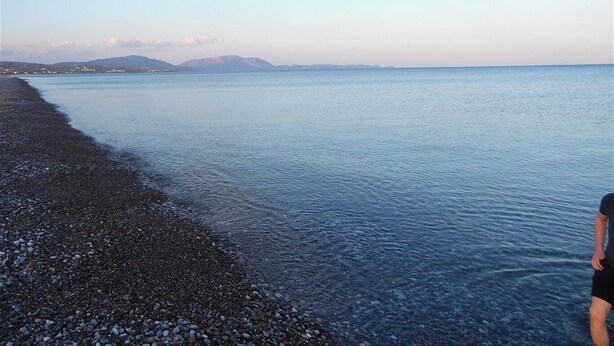 A pebbled beach with calm water and distant mountains. - Panorama Gennadi (Rhodes)