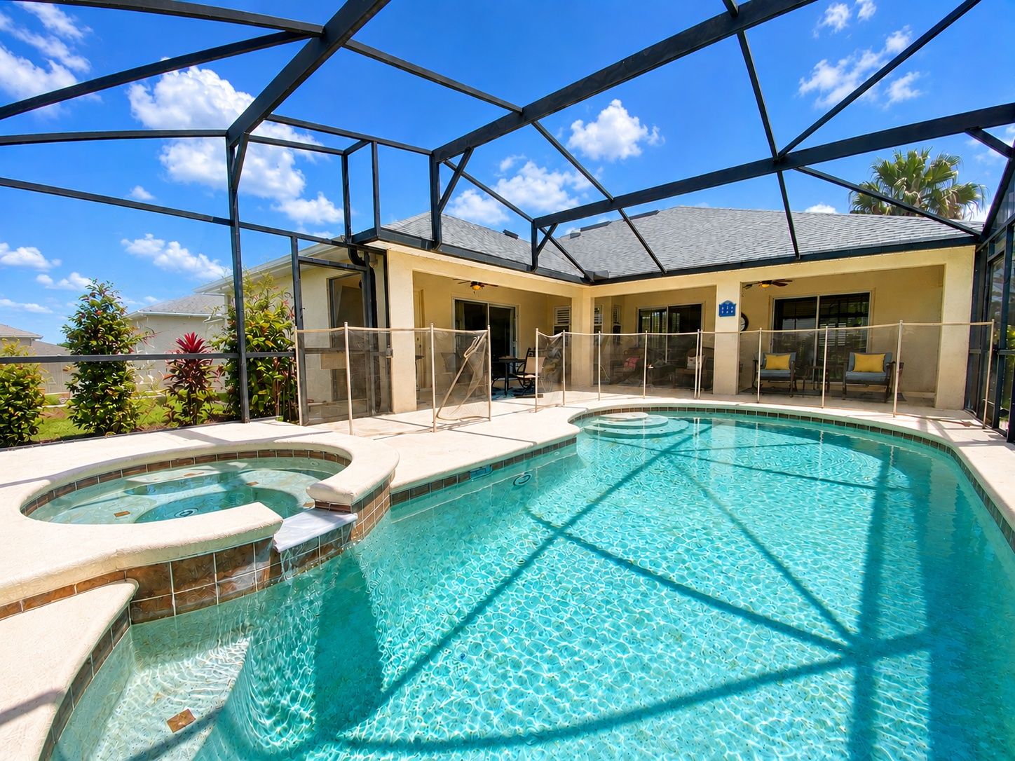 Una piscina con un jacuzzi, rodeada por una zona techada con sillas y una valla.