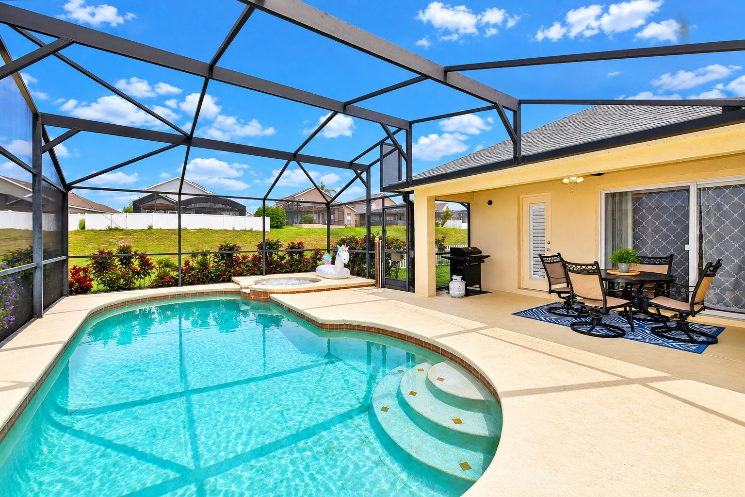 A swimming pool with a covered patio area, a barbecue grill, and outdoor seating.