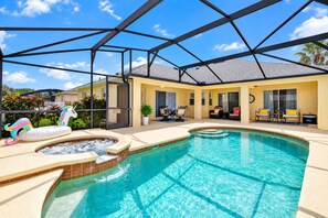 Piscina con hidromasaje, rodeada por un porche cubierto con mobiliario exterior.