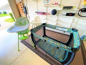 Una habitación con una trona, una cuna y una silla blanca.