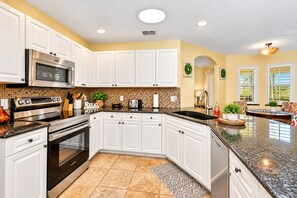 A modern kitchen with white cabinets, stainless steel appliances, and a patterned backsplash.