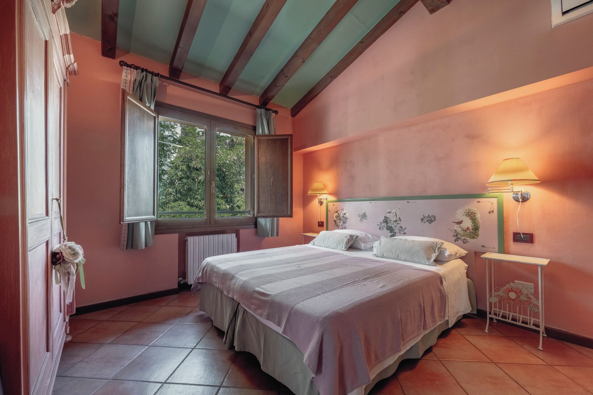Une chambre à coucher avec un lit, deux lampes de chevet, une fenêtre et un radiateur.