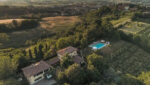 Vista aérea de uma propriedade com piscina, rodeada por árvores e campos.