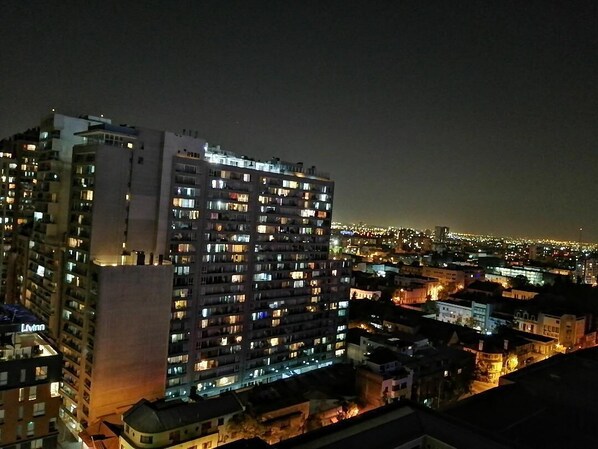 A high-rise building with multiple illuminated windows, likely a hotel or apartment complex, with a view of the cityscape at night.