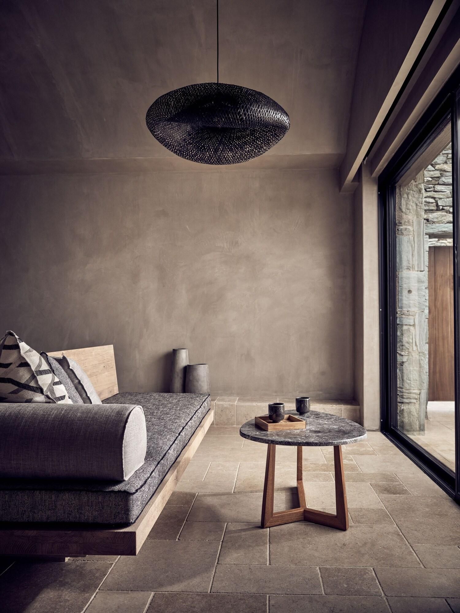 Un intérieur moderne avec un canapé, une table ronde et un luminaire suspendu.