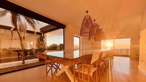 Un comedor amplio con una mesa larga y sillas, ventanas grandes y vistas al exterior.