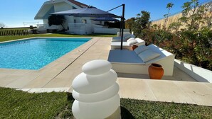 Una piscina con sillas de descanso y una pérgola.