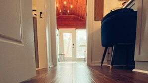 Pasillo con suelo de madera que conduce a una escalera con techo rojo y un piano.