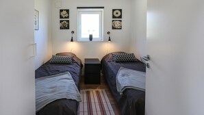A small, well-lit bedroom with two single beds, a window with a view, and a door on the right. - Beautiful home in Löttorp with WiFi (Löttorp)