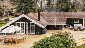 A wooden deck with outdoor furniture, a barbecue grill, and a covered patio area. - 3 bedroom stunning home in Hornbæk (Hornbæk)