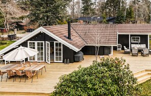 Une terrasse en bois avec des meubles d’extérieur, un barbecue et un espace patio couvert.
