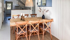 A dining area with a wooden table, six chairs, and a hanging light fixture. - 3 bedroom stunning home in Hornbæk (Hornbæk)