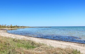 A beach with clear blue water, a sandy shore, and a breakwater extending into the sea. - 3 bedroom gorgeous home in Löttorp (Löttorp)