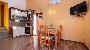 Una cucina compatta con elettrodomestici moderni, un'area pranzo con mobili in legno e un televisore a schermo piatto montato a parete.