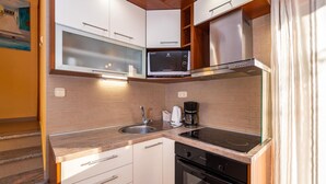 Una cucina compatta con forno a microonde, macchina del caffè e forno integrato.