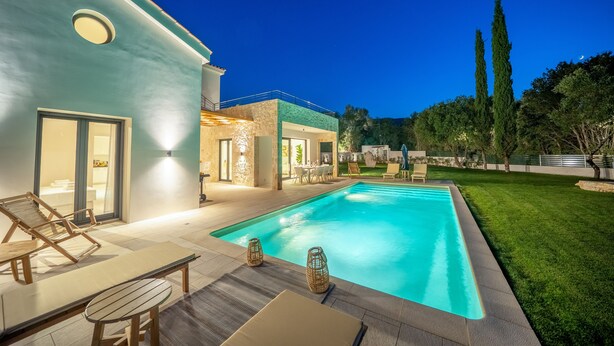 A modern house with a swimming pool, outdoor seating, and a well-maintained lawn.