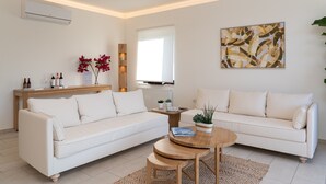 A modern living room with a white sectional sofa, a wooden coffee table, and a small side table with decorative items.