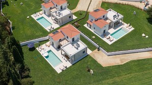 A modern residential complex with multiple houses, each featuring a swimming pool and outdoor seating areas.