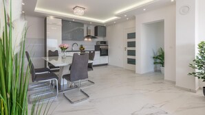 Una cocina moderna con comedor, que presenta piso de mármol, electrodomésticos de acero inoxidable y una araña.