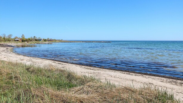 A coastal beach with a clear sky, calm water, and a distant pier. - 3 bedroom cozy home in Löttorp (Löttorp)