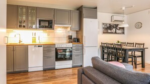 A compact kitchen with a microwave, oven, and refrigerator. There is a dining area with a table and chairs. - 3 bedroom cozy home in Löttorp (Löttorp)
