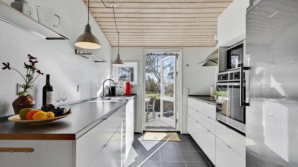 Een moderne keuken met witte kasten, een roestvrijstalen koelkast en een groot raam.