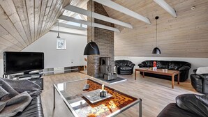 Een moderne woonkamer met een open haard, leren banken, een glazen salontafel en een flatscreen televisie.