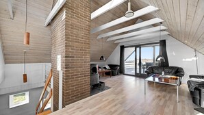 Een ruime loft met hoge plafonds, onbehandelde bakstenen muren, een open haard en grote ramen met uitzicht.