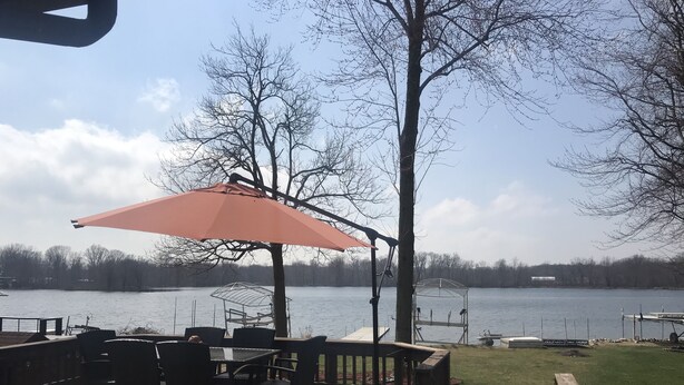 Une terrasse en bois avec des meubles d’extérieur, un espace salon abrité et une vue sur un lac.
