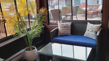 Ein Wintergarten mit Glastisch, Rattan-Sofa und Topfpflanzen.