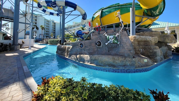 Zona de parque acuático con piscina, toboganes y decoración temática pirata.