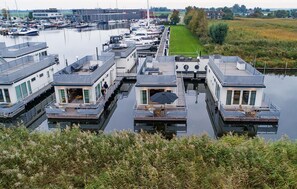 Een jachthaven met drijvende huizen, terrasjes en uitzicht op het water.